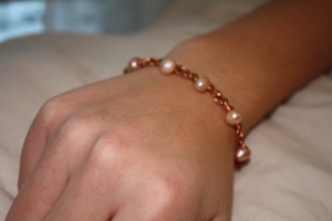 A bracelet design with salmon pearls and copper wire and chain.